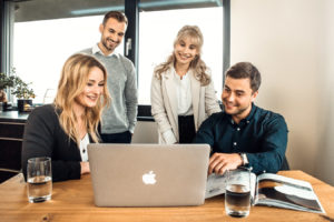 vier Angestellte schauen auf den Computer | Namox - Ihre Amazon SEO Agentur